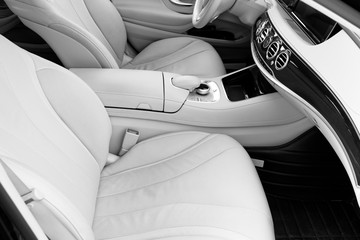 White leather interior of the lux car. Leather comfortable white seats and multimedia. Steering wheel and dashboard. Automatic gear stick. Modern car interior details. Car detailing. Black and white