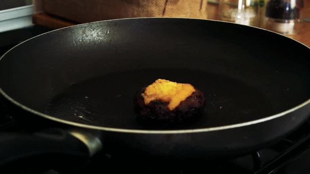 Frying a cheese burger in a frying pan. Juicy meat for a tasty meal!