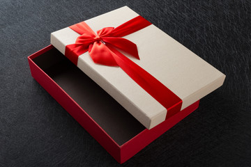 white gift box with red bow on dark background