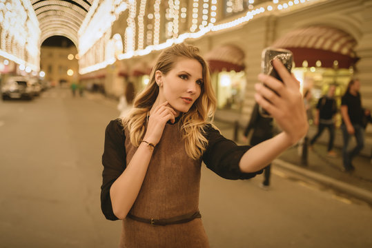 Young Happy Woman Taking Selfie At Night. Selective Focus. Color Toned.