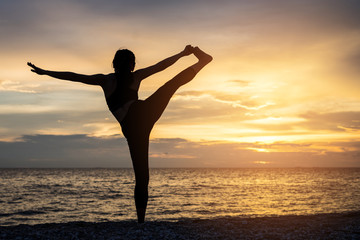 Fototapeta premium Young healthy woman practicing yoga on the beach exercise at sunset time. healthy concept.