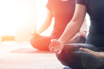 Class of yoga with meditate hands of Asia woman doing meditation in sunrise and lens flair effect.Healthcare, lifestyle concept.National Physical Fitness and Sports Month.National Yoga Awareness Month