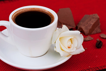 A cup of coffee on a red napkin, on an old wooden background, food is a hot drink.