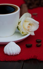 A cup of coffee on a red napkin, on an old wooden background, food is a hot drink.