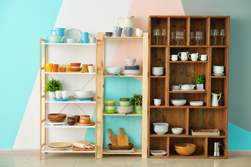 Kitchen shelving with dishes on color wall background
