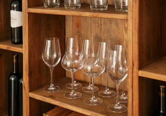 Wine glasses on shelf of wooden storage stand indoors