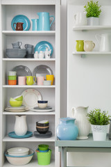 White storage stand with colorful ceramic dishware indoors