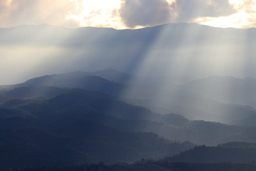 Dramatic god lights passing through clouds and shining on mountain ranges. warm light shower. God...