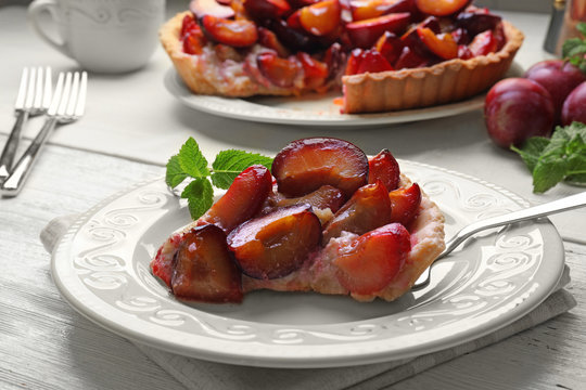 Delicious piece of pie with plums on plate