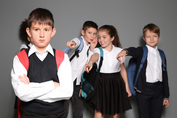 Children bullying their classmate on grey background