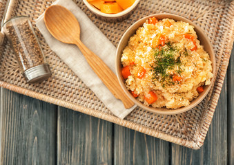 Bowl with delicious pumpkin risotto on wicker tray