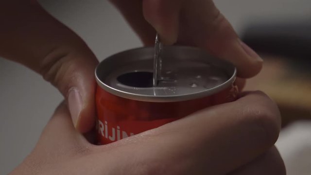 Close up of a can of coke being opened.