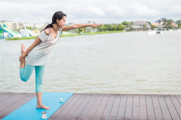 woman practicing yoga and meditation on mat near lagoon. sport and health concept  with copy space for text.