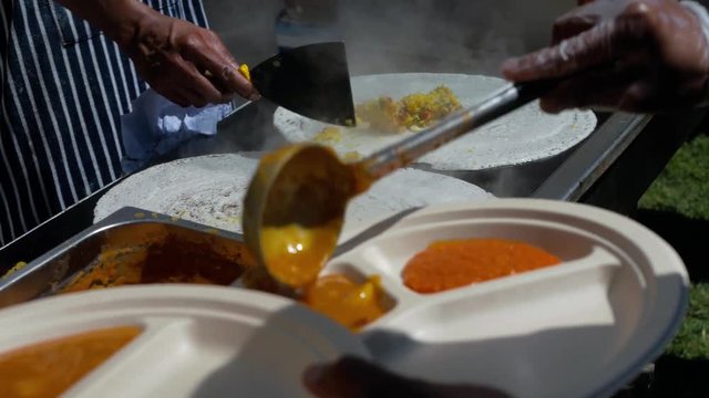 Chef from Rishis Glasgow making malala dosas and serving on to plates at Glasgow Mela