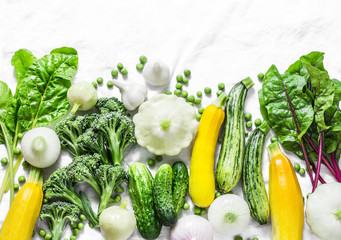 Fresh organic vegetables - zucchini, squash, cucumbers, broccoli, onions, garlic, chard, green peas on a light background, top view. Healthy lifestyle diet vegetarian food concept. Flat lay