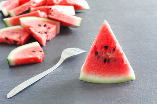 Pieces of juicy ripe watermelon slices with  fork on  stone countertop