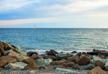 Beautiful seascape.  Stones, yacht, sea and blue sky