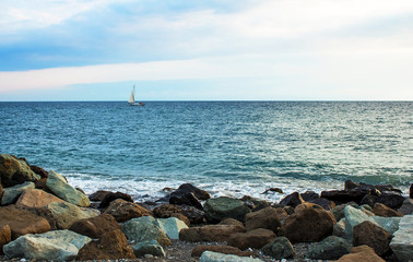 Beautiful seascape.  Stones, yacht, sea and blue sky
