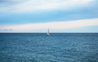 Beautiful seascape.  Stones, yacht, sea and blue sky