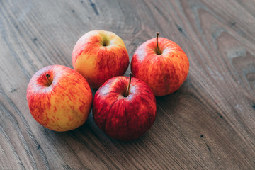 A bunch of apples lay on top of a dark wood table