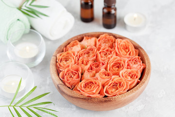 Obraz na płótnie Canvas Bowl with fresh wet rose and essential oil bottle for spa, wellness and aromatherapy.