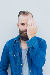 Bearded man covering one eye with his hand