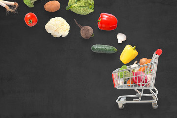 Fresh organic vegetables fall into the basket on a dark board. Composition