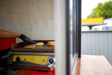 Chef cooking cutlet and bun on grill for perfect burger in a street cart.