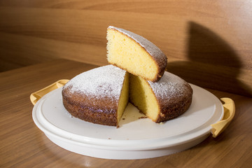 Slice of a delicious cake with powdered sugar on a wood table