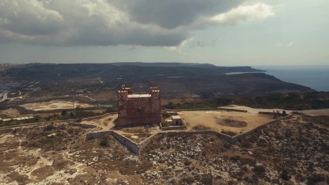 Far Aerial shot rotating around St Agatha's Red Tower in Mellieha Malta