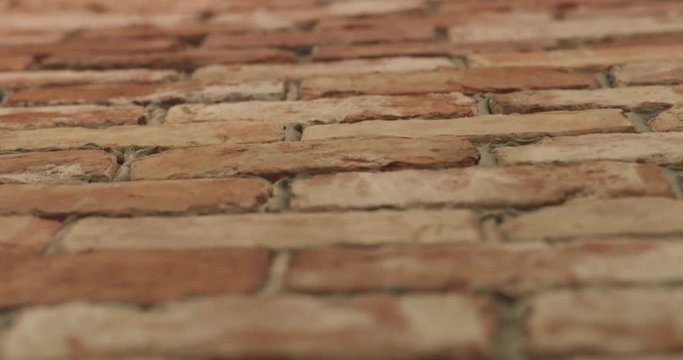 Slow motion handheld closeup pan of filled seams on brick wall