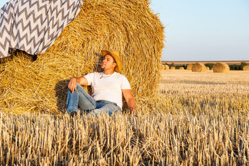 Naklejka na ściany i meble Cute man resting after hay harvesting in haystacks