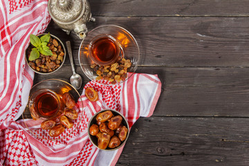 Traditional Arabic, Turkish Ramadan tea with dry dates and raisins on a wooden black table. Ramadan. Turkish fresh tea with dates. View from above.