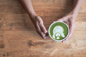 Green tea matcha latte in a cup on wooden background