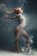 Dancing in flour concept. Redhead cute female girl adult woman dancer in dust / fog. Girl wearing...