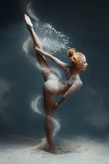  Dansen in meelconcept. Redhead schattig vrouwelijk meisje volwassen vrouw danseres in stof/mist. Meisje met witte top en korte broek die danselement maakt in bloemwolk op geïsoleerde grijze achtergrond © Monstar Studio