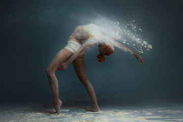 Dancing in flour concept. Redhead beauty female girl adult woman dancer in dust / fog. Girl wearing white top and shorts making dance element in flour cloud on isolated grey background