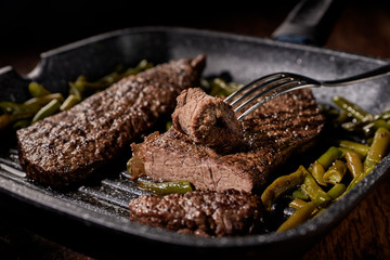 steak in a frying pan with green beans