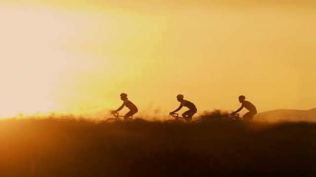 Pan tracking of group of road bikers silhouette in the morning