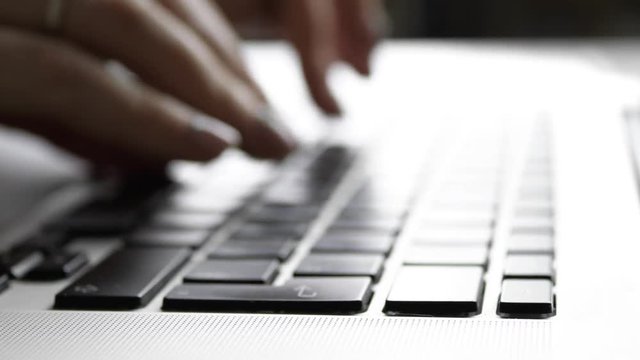 Fingers typing on a laptop, blue tone