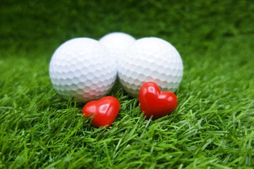 Fototapeta premium Golf ball with heart shape for golfer lover are on green grass