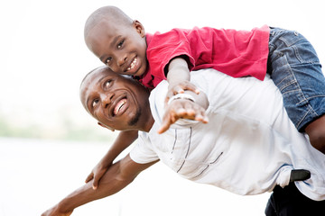 young father carrying his son smiling on his back