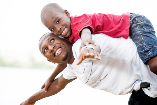young father carrying his son smiling on his back