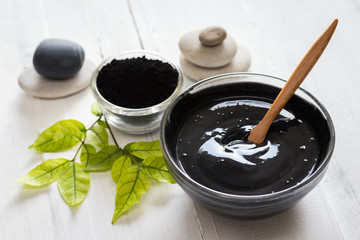 Homemade facial mask and scrub by activated charcola powder and yogurt on white wooden background