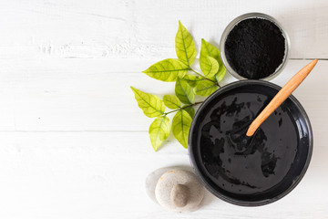 Homemade facial mask and scrub by activated charcola powder and yogurt on white wooden background