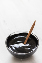 Homemade facial mask and scrub by activated charcola powder and yogurt on white wooden background