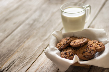 Chocolate chips cookies and a glass of milk on wooden background, homemade sweet and dessert concept