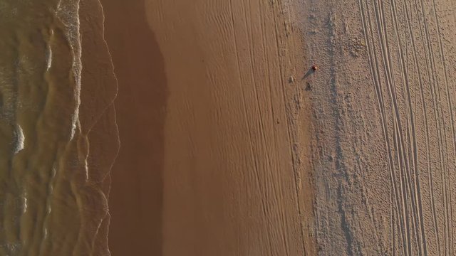 Tire marks on an empty beach and waves hitting the shore