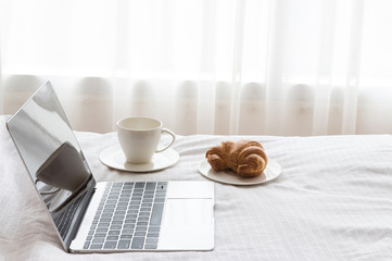 Laptop pc and a cup of coffee on the bed in the morning. Lifestyle Concept