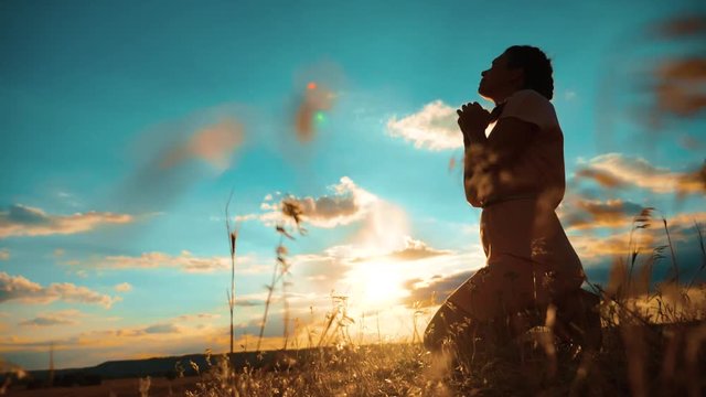 girl praying. girl folded her hands lifestyle in prayer silhouette at sunset. slow motion video. Girl folded her hands in prayer pray to God. asks forgiveness for sins of repentance. believing girl
